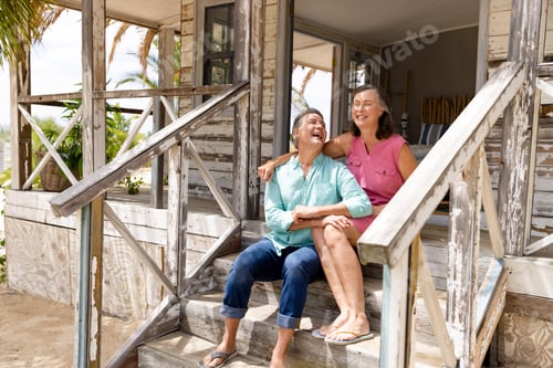 Aperçu: Ecstatic caucasian senior couple talking and laughing while sitting on staircase outside cottage