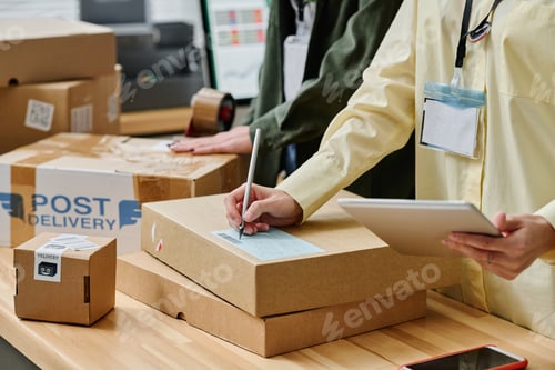 Preview: Close-up of young woman with tablet and pen writing down address on box