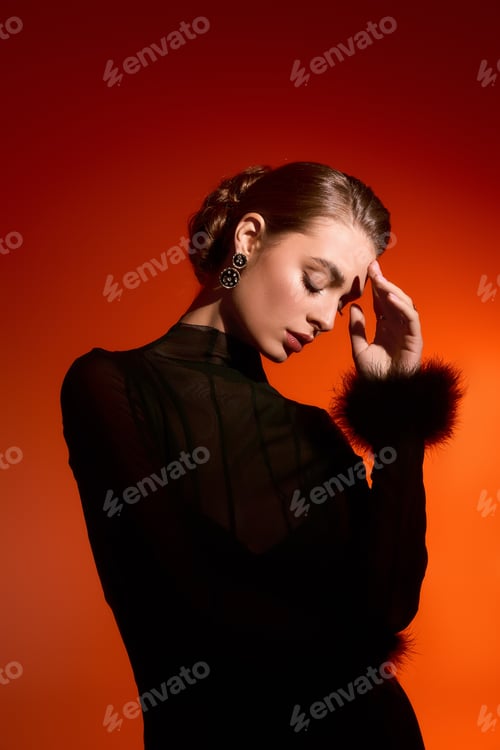 Preview: Elegant young woman poses gracefully against a vibrant orange background