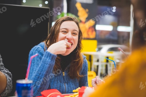 Preview: young blonde woman eating in fast food with friends