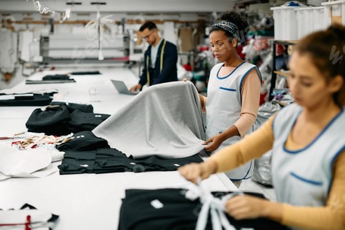 Preview: African American textile factory employee working with fabric at production line.