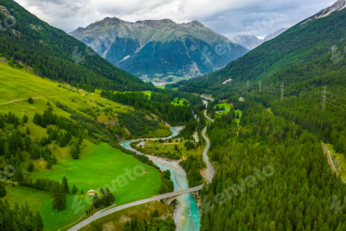 Preview: Inn River flowing in the forest in Switzerland. Aerial view from drone on a blue river in the