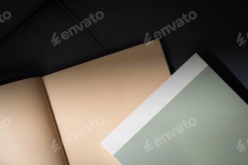 Preview: Stack of Magazines on a Black Leather Couch in Soft Light