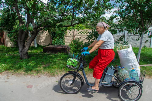 Preview: An old woman rides a bicycle. Selection focus.