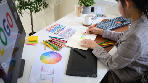 Preview: reative designer developing branding idea with color pencils, palette, and digital tablet