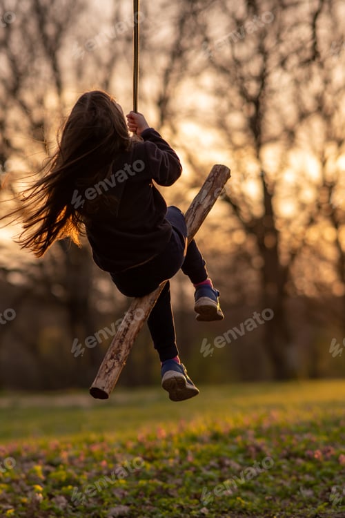 Preview: Unrecognizable girl swings on homemade swing in nature, in park, in village, in children's camp