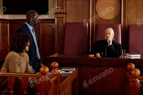 Preview: Confident experienced female judge sitting in front of elegant attorney