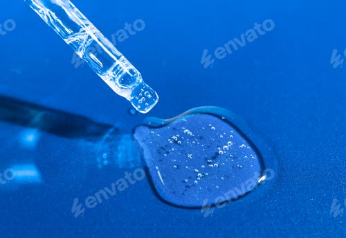 Preview: Glass pipette with transparent serum, hyaluron on a bright blue background.