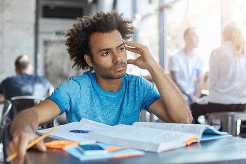 Preview: Portrait of attractive male with stylish hairstyle writing composition on free topic keeping his han