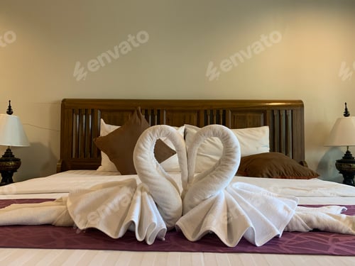 Preview: Beautiful white swan made from towel in heart shape at hotel room.