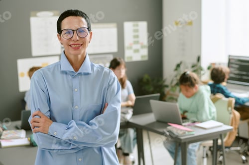 Preview: Portrait of Middle Aged Caucasian Woman Smiling in Classroom with Students Working