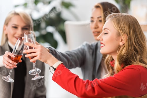 Preview: successful fashionable businesspeople clinking with champagne glasses in modern office