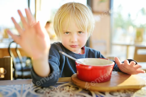 Preview: Little boy sitting the table in cafe or restaurant and doesn't want to eat. Healthy food. Kids diet.