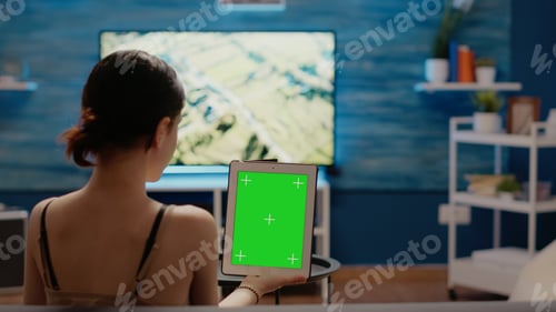 Preview: Caucasian woman holding green screen vertically on digital tablet