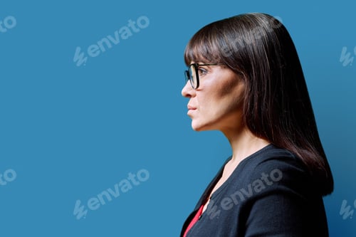 Preview: Profile view of middle aged serious woman, blue background, copy space