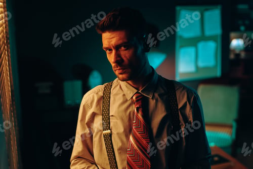 Preview: Young serious man in shirt, tie and suspenders looking at camera