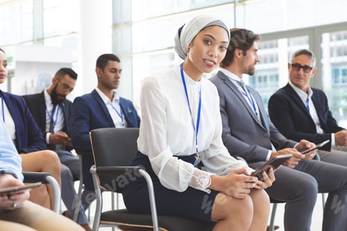 Preview: Businesswoman with digital tablet looking at camera in seminar