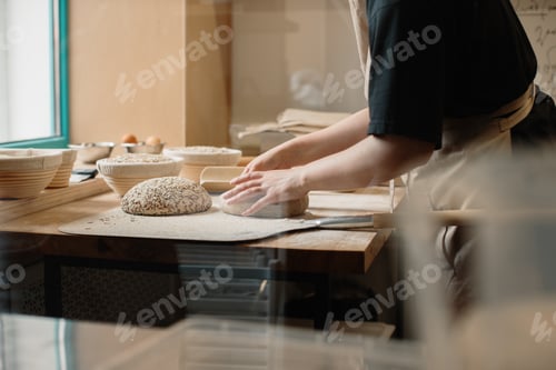 Preview: The baker sprinkles flour on the raw bread lying on the peel.