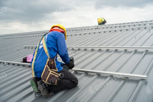Preview: Men technicians mounting photovoltaic solar moduls on rooftop of warehouse.