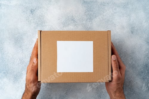 Preview: Parcel cardboard box in a man hands on a gray table background
