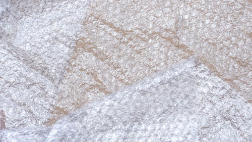 Preview: Flat lay of white plastic bubble wrap on cardboard paper sheet background