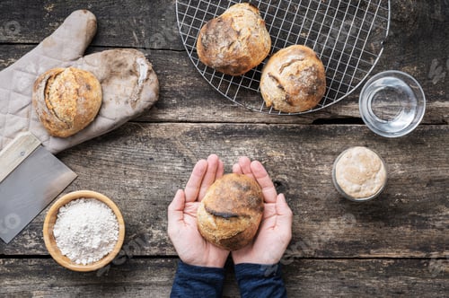 Preview: Top view of male hand holding freshly baked homemade bread bun
