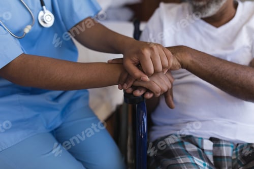 Preview: Mid section of young African American female doctor consoling senior African American man at home