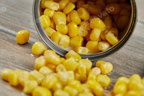 Preview: A can of boiled sweet corn on a wooden table with a spoon