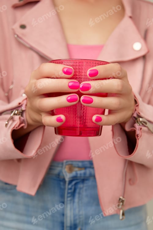 Preview: Womans hands holding pink glass. Manicure, pedicure beauty salon concept