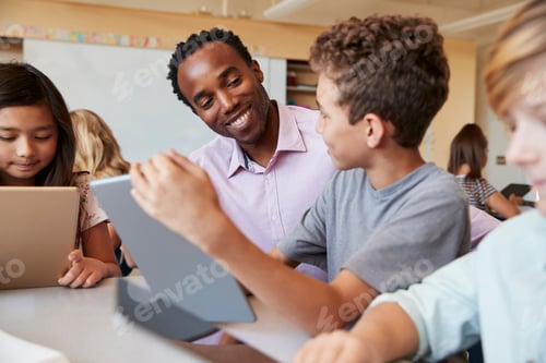 Preview: Teacher using tablet computer at desk with school kids