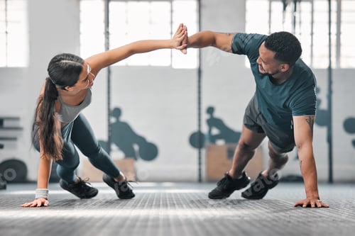 Preview: Healthy, fit and active gym partners exercising together and doing pushups with a high five. Boyfri