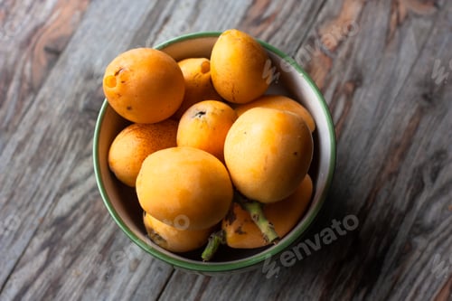 Preview: Ripe medlar fruit (Eriobotrya japonica) in green cup on wooden table. Top view.