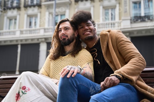 Preview: Gay couple sitting on bench, embracing and smiling