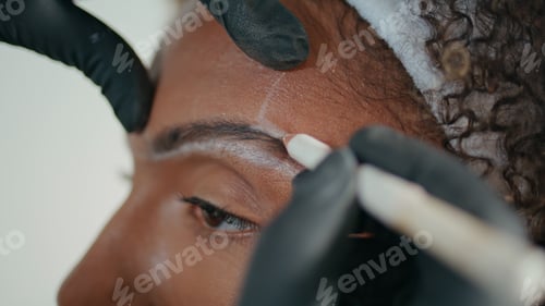 Preview: Closeup cosmetician marking brows with pencil. Hands in gloves shaping contour