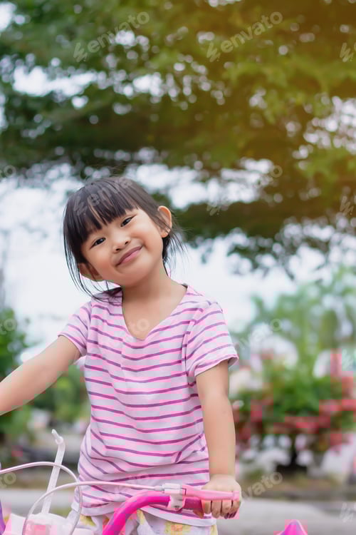 Visualização: Imagem do retrato da menina asiática fofa feliz andar de bicicleta no parque. Exercício infantil e esporte.