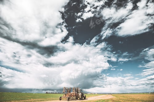 Preview: Tractor With Attached Harrow In Sunny Spring Day. Countryside Rural Road Through Field Meadow
