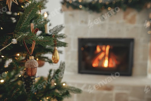 Preview: Stylish christmas gold acorn on tree close up against burning fireplace