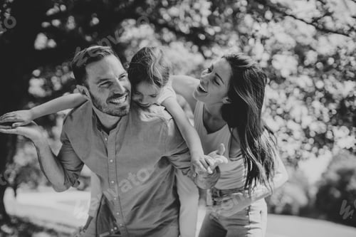 Vista previa: Familia joven feliz con una linda hija divirtiéndose en el parque en un día soleado