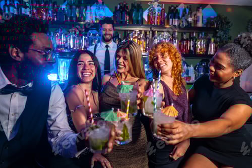 Preview: Friends toasting cocktails in nightclub with bartender