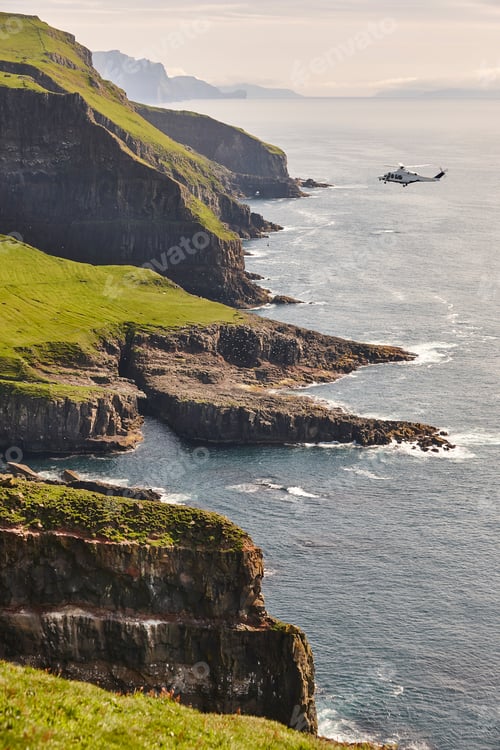 Preview: Helicopter flying over mykines atlantic cliffs in Faroe islands. Transportation