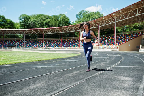 Preview: Portrait of a strong fit girl in sportswear running in the stadium.