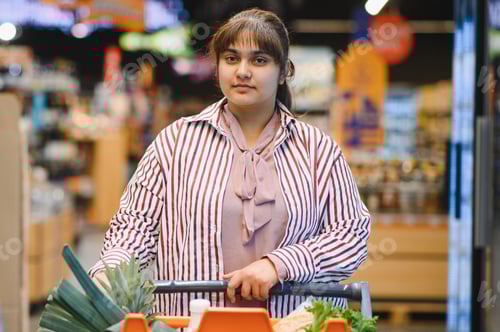 Preview: Young indian woman pushing shopping cart in grocery store