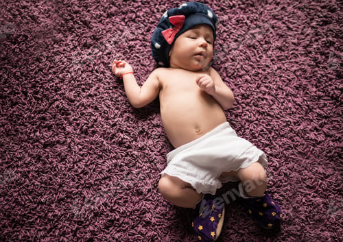 Preview: Little newborn with a hat on head sleeps sweetly