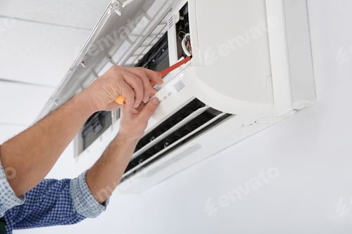 Preview: Electrician with screwdriver repairing air conditioner indoors, closeup