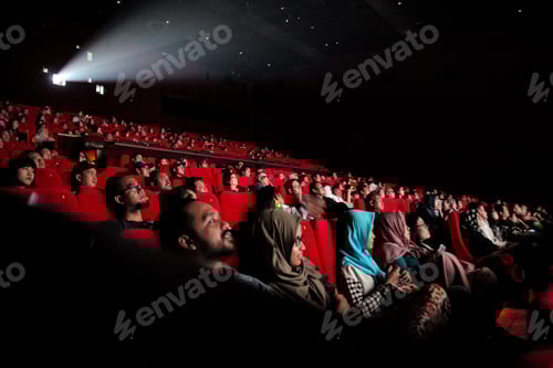 Preview: Diverse Audience Watches Film In Dark Movie Theater, Illuminated By The Projector's Beam