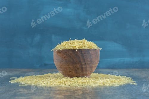 Preview: Vermicelli pasta scattered from a full bowl , on the marble background