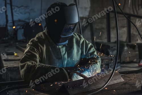 Preview: manual worker in protective helmet with welding torch working in workshop