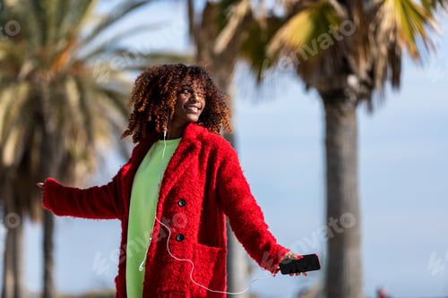 Preview: Young afro american woman laughing while dancing outdoors