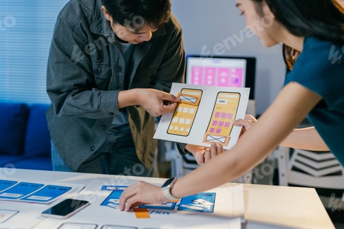 Preview: Two asian designers collaborate on a mobile app in a busy office. They focus on user experience and