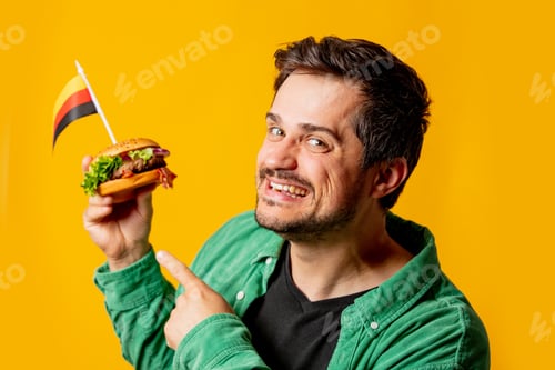 Preview: Smiling man with burger and german flag on yellow background